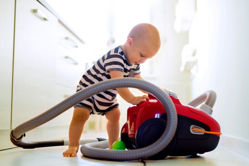 Baby boy with the hoover in the kitchen.