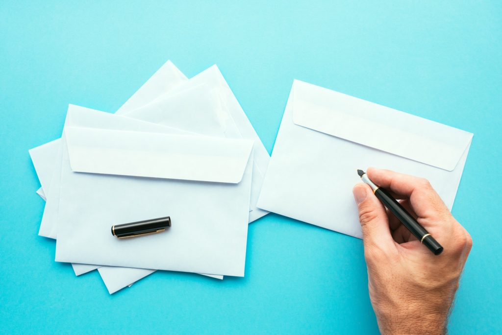 Hand writing address on blank white envelope