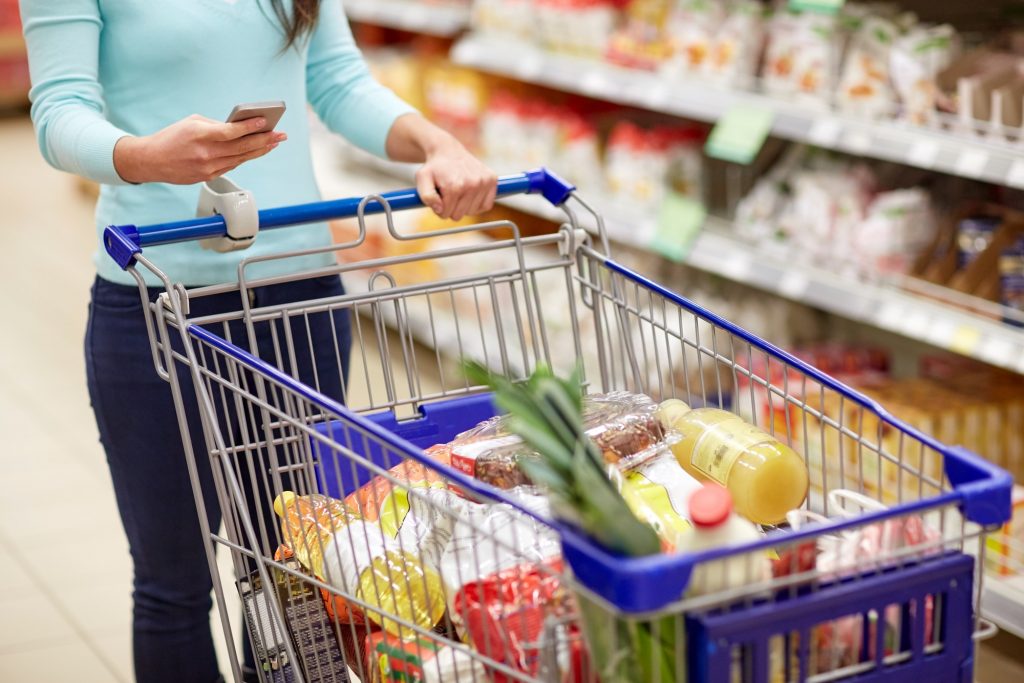 woman with smartphone buying food at supermarket