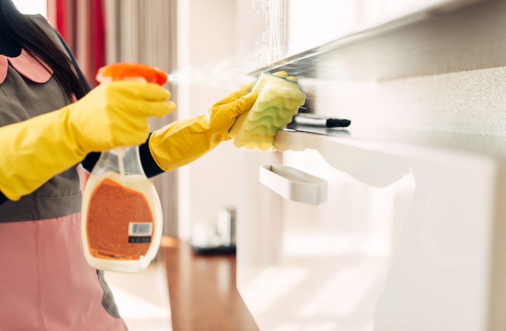 Housemaid cleans furniture with a cleaning spray